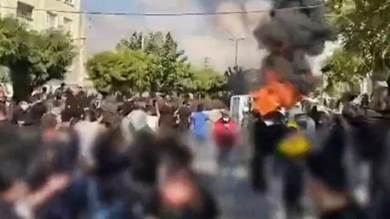 لقطة من مقطع فيديو نشره ناشطون معارضون يظهر محتجين على مقربة من مركبة مشتعلة في منطقة كرج غربي العاصمة الإيرانية طهران